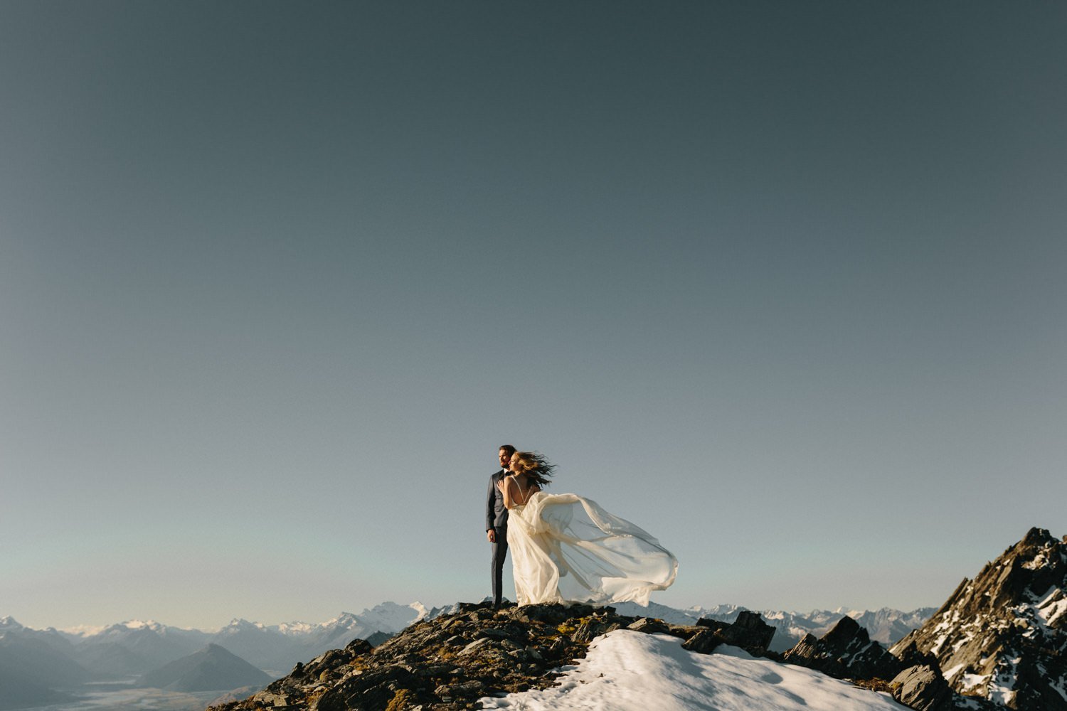 Soft and floaty bridal gown blowing in the wind with Glenorchy mountains in the background for a mountain top elopement.